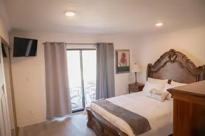 a bedroom with a large bed and a balcony at Surfside Four in Port Hueneme