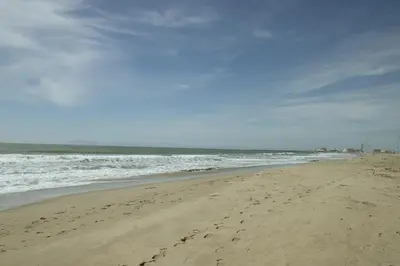 a beach with footprints in the sand and the ocean at Surfside Four in Port Hueneme