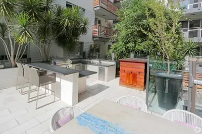 an outdoor patio with a grill and tables and chairs at The Amber Serene Peaceful Retreat Pool Gym And Jacuzzi in Los Angeles
