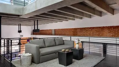 a living room with a couch and a brick wall at Skyline Lofts by AvantStay: a multi-level industrial-chic retreat in DTLA with rooftop views soaring ceilings steps to dining music culture in Los Angeles