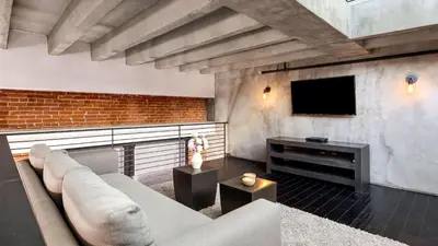 a living room with a couch and a flat screen tv at Skyline Lofts by AvantStay: a multi-level industrial-chic retreat in DTLA with rooftop views soaring ceilings steps to dining music culture in Los Angeles