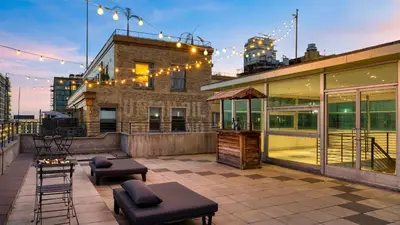 a rooftop patio with a bar on a building at Skyline Lofts by AvantStay: a multi-level industrial-chic retreat in DTLA with rooftop views soaring ceilings steps to dining music culture in Los Angeles