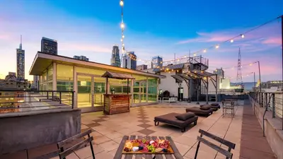 a rooftop patio with tables and chairs on a building at Skyline Lofts by AvantStay: a multi-level industrial-chic retreat in DTLA with rooftop views soaring ceilings steps to dining music culture in Los Angeles