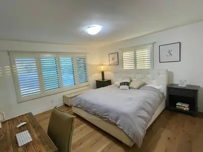 a bedroom with a bed and a table and windows at Spectacular City Mountain Views Remodeled Open Plan 3 bdr Home Pool Jacuzzi Oasis in Engine Company Number 109 Heliport