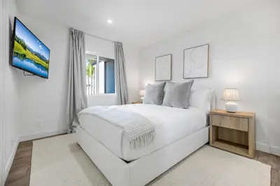 a white bedroom with a white bed and a tv at Rancho Haven in Los Angeles