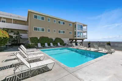 a swimming pool with lounge chairs and a building at Playa Del Sol by Stay Awhile Villas in Malibu Beach