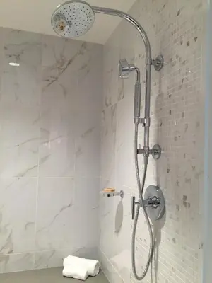 a bathroom with a shower with white tile at Parkwest Bicycle Casino in Bell Gardens