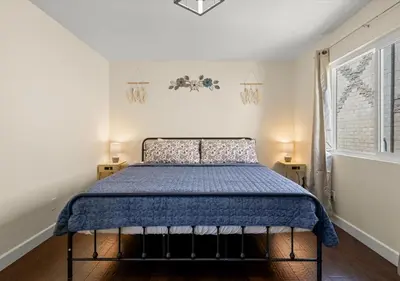 a bedroom with a bed with a blue comforter and a window at Cozy&Stylish DT Alhambra Living walk to Starbucks in Alhambra