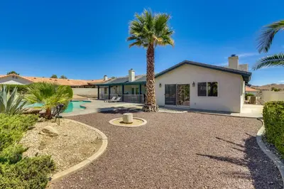 a palm tree in front of a house at Pool, Spa and Mountain Views Apple Valley Retreat! in Apple Valley