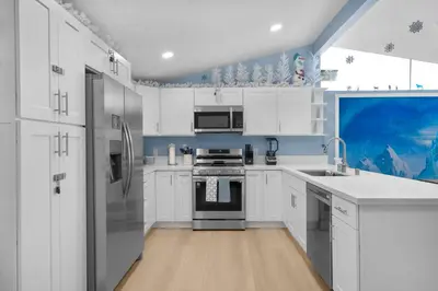 a kitchen with white cabinets and a stainless steel refrigerator at Enchanted Dreams by OC Adventure Homes in Garden Grove