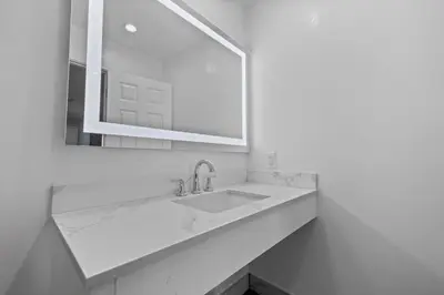 a white bathroom with a sink and a mirror at Downey Inn in Downey