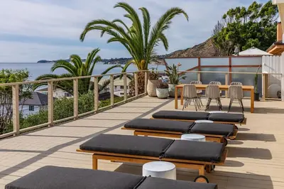 a deck with lounge chairs and a table and the ocean at The Hideaway Beach House by Stay Awhile Villas in Malibu Beach