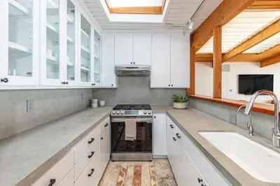 a kitchen with white cabinets and a stove top oven at The Hideaway Beach House by Stay Awhile Villas in Malibu Beach