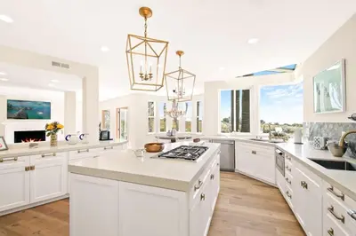 a large white kitchen with white cabinets and a chandelier at Villa Azure - by Stay Awhile Villas in Malibu
