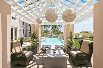 a patio with chairs and a table and a pool at Villa Azure - by Stay Awhile Villas in Malibu