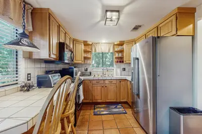 a kitchen with wooden cabinets and a stainless steel refrigerator at Couples Retreat Near Lake Arrowhead and Hiking! in Lake Arrowhead