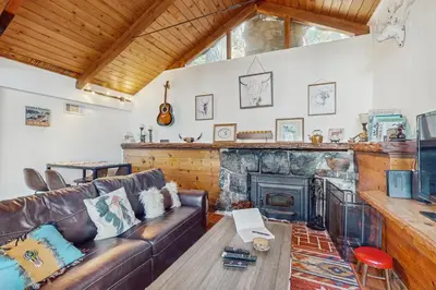 a living room with a leather couch and a fireplace at Couples Retreat Near Lake Arrowhead and Hiking! in Lake Arrowhead