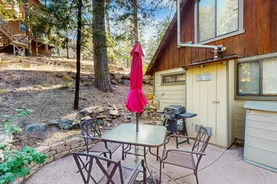a table with chairs and an umbrella on a patio at Couples Retreat Near Lake Arrowhead and Hiking! in Lake Arrowhead