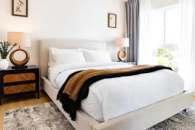 a bedroom with a bed with white sheets and a window at Grand 4-Bedroom - Brand New - Free parking and Patio in Los Angeles