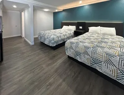 a hotel room with two beds and wooden floors at Studio 6 Suites Buena Park CA Anahiem Near Maingate Knotts in Buena Park