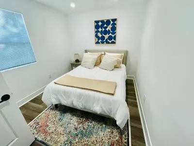 a white bedroom with a bed and a rug at Modern LA Guest House in Los Angeles