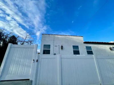 a white house with a white fence and a blue sky at Modern LA Guest House in Los Angeles