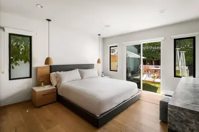 a bedroom with a large white bed and a patio at NEW! High-End Spanish Duplex | Luxury 3BR in Los Angeles