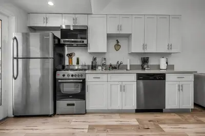 a kitchen with white cabinets and stainless steel appliances at Loft-Style 1-Bedroom Apartment with Balcony & Private Parking in Hollywood in Los Angeles