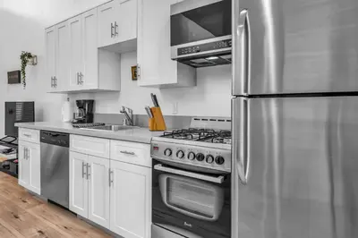 a kitchen with white cabinets and a stainless steel refrigerator at Lux Hollywood Loft 1BR with Balcony & Private Parking 10 Min to Downtown LA in Los Angeles