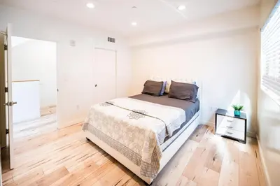 a white bedroom with a bed and a wooden floor at Chic Hollywood Koreatown 3Bedroom Loft 3 Level 2 Bathrooms Perfect for Groups up to 10 in Los Angeles