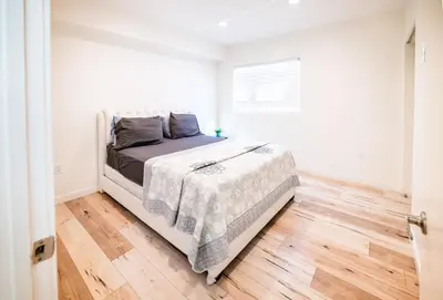 a white bedroom with a bed and a wooden floor at Chic Hollywood Koreatown 3Bedroom Loft 3 Level 2 Bathrooms Perfect for Groups up to 10 in Los Angeles