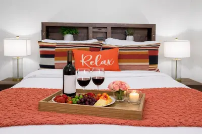 a tray of fruit and wine on a bed at Modern 1BR Suite w AC Sleeps 3, NW Bakersfield in Bakersfield