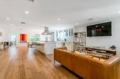 a living room with a brown couch and a kitchen at Spacious 4BR Games Workspace Outdoor Fun in Los Angeles