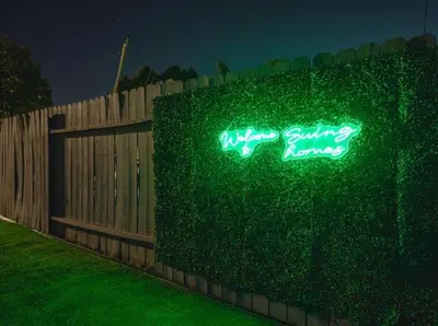 a fence with a green neon sign on it at \u8fd1ONT\u673a\u573aChaffeyClaremont \u5b66\u9662Outlets1B1B in Rancho Cucamonga