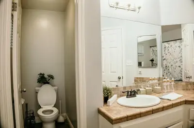 a bathroom with a sink and a toilet and a mirror at Stunning Home with Pool, Game Room and Firepit in Bakersfield