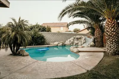a swimming pool in a yard with palm trees at Stunning Home with Pool, Game Room and Firepit in Bakersfield