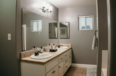 a bathroom with two sinks and two mirrors at Stunning Home with Pool, Game Room and Firepit in Bakersfield