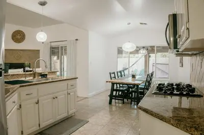 a kitchen with white cabinets and a table with a stove at Stunning Home with Pool, Game Room and Firepit in Bakersfield
