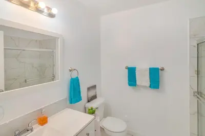 a white bathroom with a toilet and a mirror at HOV Lux Whitehouse Lakeview Terrace