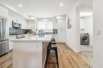 a kitchen with white cabinets and a counter with stools at NoHo Modern Townhouse with Gorgeous Rooftop in Van Nuys