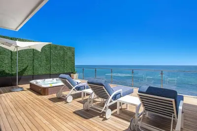 three chairs and a table on a deck with the ocean at Casa Mare by Stay Awhile Villas in Malibu Beach