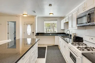 a kitchen with white cabinets and a stove top oven at Between LA and Orange County Quiet Getaway with Patio in Pico Rivera