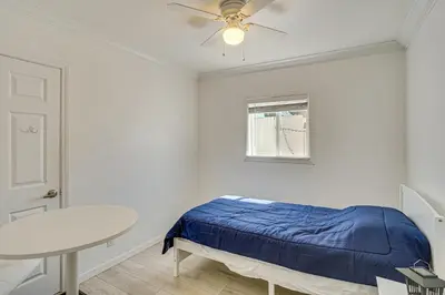 a bedroom with a bed and a table and a ceiling fan at Between LA and Orange County Quiet Getaway with Patio in Pico Rivera