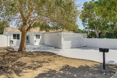 a garage with a tree and a white fence at Between LA and Orange County Quiet Getaway with Patio in Pico Rivera