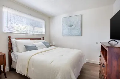 a white bedroom with a bed and a television at Stylish2BR Patio BBQ Parking Downtown LA in Los Angeles
