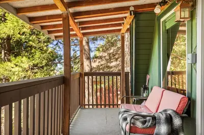 a porch with a rocking chair on a green house at Casa Huntsted A-Frame Cabin near Snow Valley in Running Springs