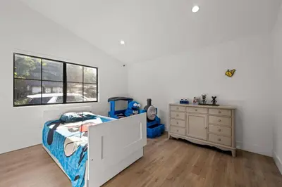 a bedroom with a bed and a dresser and a window at Coulson Street Retreat with pool BBQ and more in Los Angeles