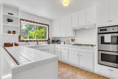 a white kitchen with white cabinets and a window at Peaceful, Los Angeles Family Vacation, Relocation Home in Los Angeles