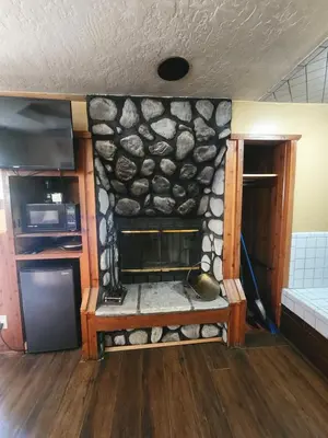 a room with a stone wall with a fireplace at Creek Runner Lodge in Big Bear Lake