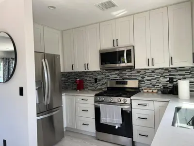 a kitchen with white cabinets and a stove and a microwave at Cheerful house with EV, Parking & backyard in Los Angeles